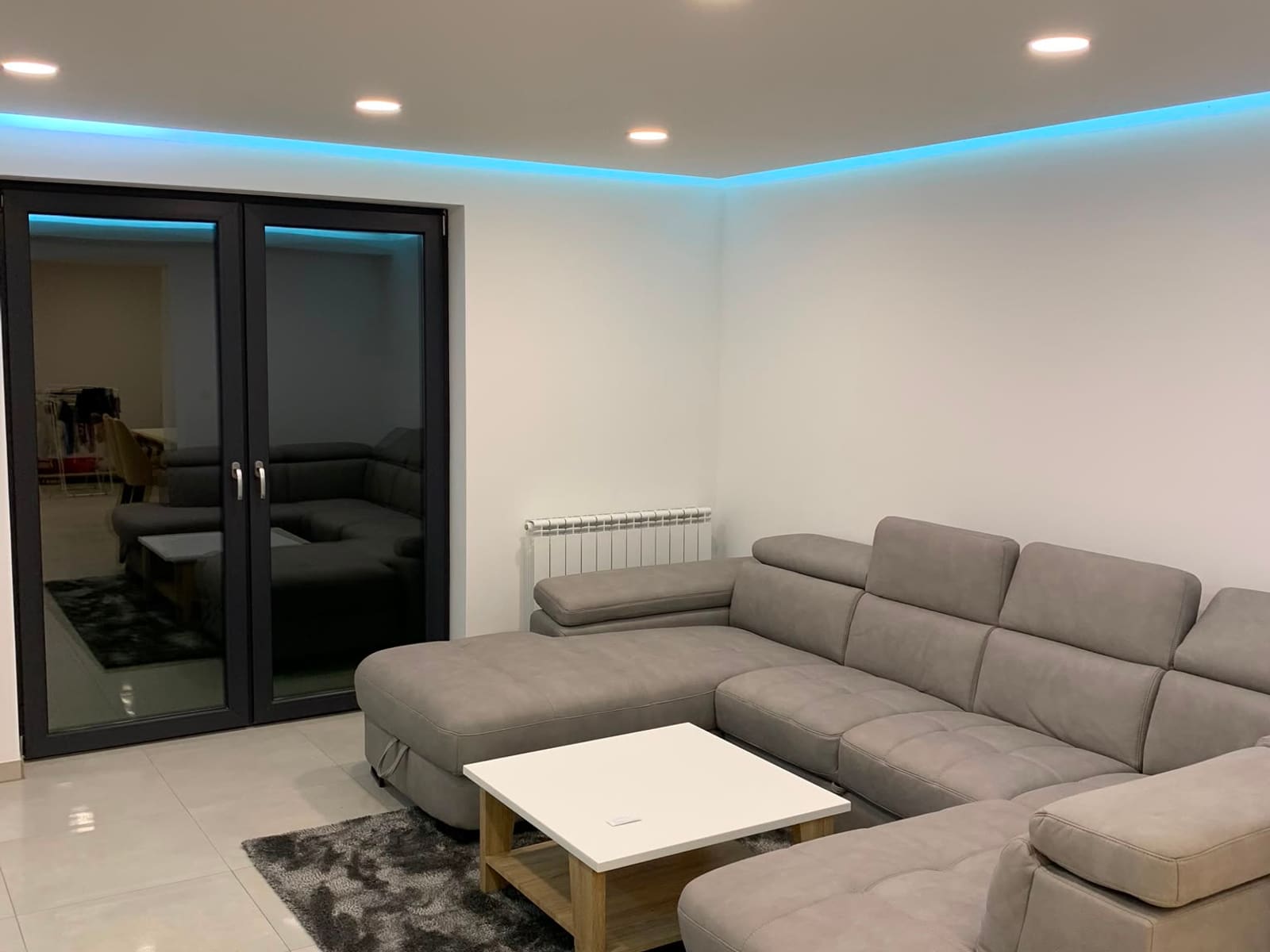 Fertig renovierter Wohnraum mit Sofa, Fliesenboden und indirekter Deckenbeleuchtung