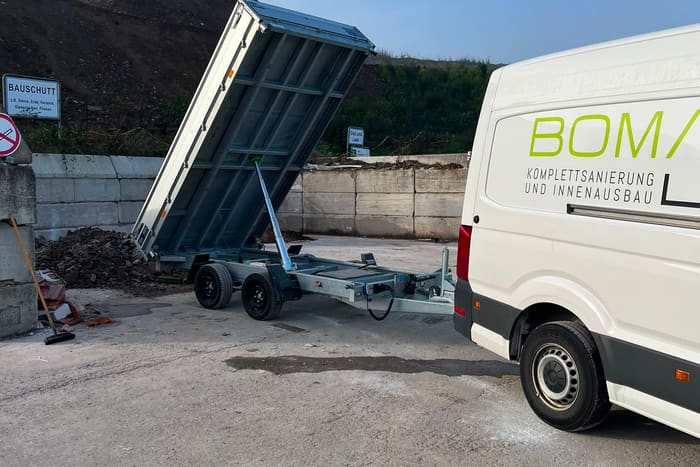 Firmenfahrzeug von BOMA Objektservice mit gekipptem Anhänger bei der Entsorgung von Bauschutt